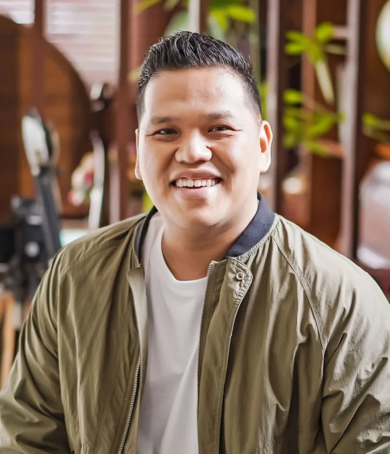 Smiling person in green jacket indoors