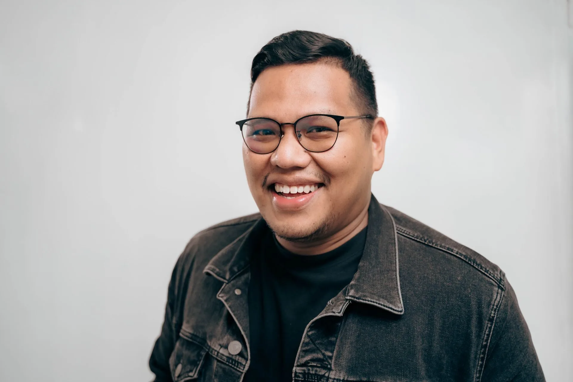 Smiling person wearing glasses and denim jacket