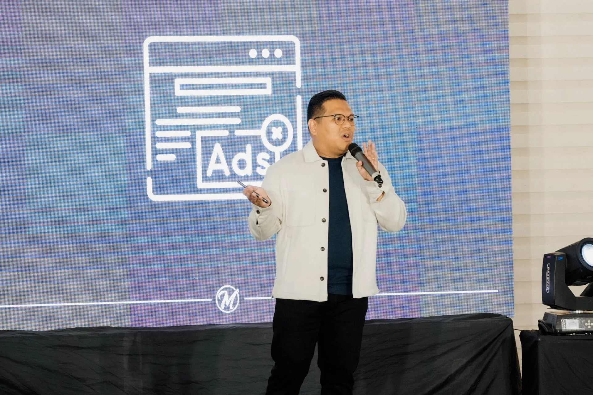 Person speaking with projected ads graphic on screen.