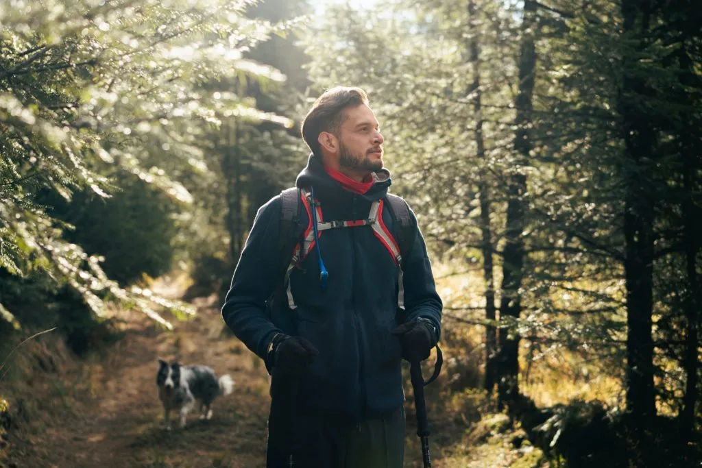 Man hiking with dog in forest
